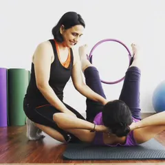 I am assisting a student during a certification course, using the magic circle to help her understand the mechanics of a core exercise. This shows the hands-on nature of my training.