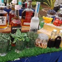 A selection of premium spirits alongside fresh herbs like rosemary and basil. This showcases the quality ingredients I use, combining top-shelf liquor with garden-fresh elements for superior cocktails.