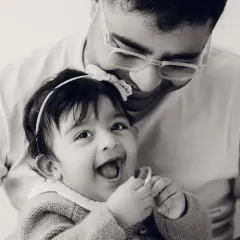 A father and daughter share a laugh in this sweet black and white close-up. The focus is entirely on their happy connection.