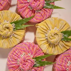 A vibrant flat lay of gifts wrapped in traditional Indian block-printed fabric from Doro. The bright colors and seashell details create a unique and culturally rich visual for festive gifting.