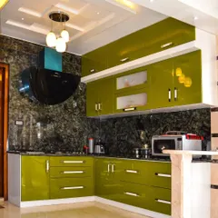 This kitchen makes a bold statement with vibrant, lime-green high-gloss cabinets. The striking color is balanced by a dark marble backsplash and a coffered ceiling with a modern chandelier, creating a cheerful and energetic atmosphere.