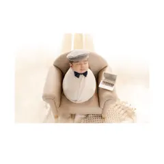 The little boss. A newborn, swaddled and wearing a dapper cap and bow tie, sleeps in a miniature armchair with a tiny laptop. This humorous and adorable themed shot shows the creative possibilities of a newborn session.