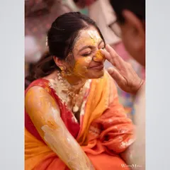 A close-up shot of the bride's smiling face as turmeric is gently applied. This image captures the intimate and personal nature of the Haldi ritual.