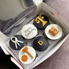 Cupcakes for a lawyer's birthday. This set features fondant toppers shaped like a gavel, law book, and scales of justice for a fun, professional theme.