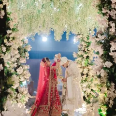 The Varmala exchange, framed by a magnificent floral arch. This is the moment of union, captured with a sense of grandeur and beauty.