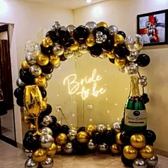 This black, gold, and silver 'Bride to be' theme is perfect for a nighttime celebration. The neon sign glows beautifully against the balloon arch, and the champagne and glass props add a fun, celebratory touch.
