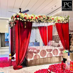 A luxurious and romantic bedroom decoration for a wedding night or anniversary. We created a four-poster bed effect with rich red drapes, a canopy of fresh flowers, and scattered rose petals on the floor.
