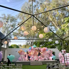 I love transforming unique venues. This transparent tent allowed us to build a beautiful butterfly garden party indoors while still feeling connected to the nature outside, with string lights and paper lanterns adding to the magical evening ambiance.