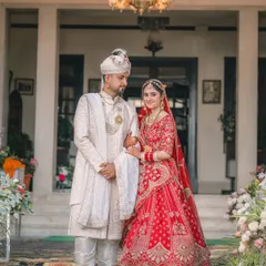 A timeless full-length portrait of the bride and groom in their wedding attire, standing before the entrance of the heritage venue.