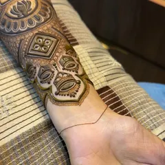 The beginning stages of an elaborate arm band. This design features traditional motifs like the 'kalash' (pot) and lotus, which are symbols of prosperity and purity.