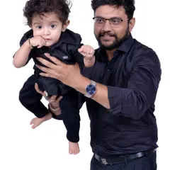 A father and son portrait with matching black shirts against a clean white background. These simple, coordinated shoots are a great way to capture the bond between a parent and child.