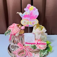 Pretty in pink! This 'Baby Girl' announcement hamper is set on a mirror base and includes a decorative jar and a sweet potli.