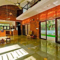 The interior of the Vidyut Kapoor Residence reveals a double-height living space, a signature element in our designs. This feature, combined with expansive glass doors and exposed brick walls, creates an airy, light-filled home that seamlessly connects to the surrounding green space.
