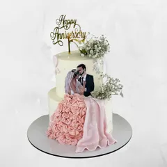 I love making cakes that tell a story. This two-tier anniversary cake features an edible image of the couple, framed by a cascade of hand-piped pink fondant ruffles.