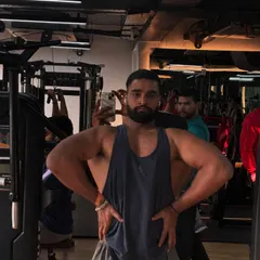 Hard work pays off. This member takes a moment to capture his progress in the gym mirror, showing the back and shoulder development that comes from consistent training.