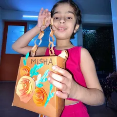 A proud creator showing off her personalized paper bag purse. She designed the floral decorations and even added her name, making it a truly unique accessory.