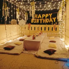 A slightly different angle of the same terrace party, showing the 'Happy Birthday' foil balloons that add a classic celebratory touch to the magical lighting.
