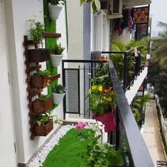 A wide angle view of a multi level balcony garden. We installed a vertical planter system on the wall and arranged various flowering plants along the railing to create a lush, layered effect.