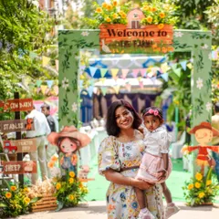 A happy welcome to the farm! The birthday girl and her mom pose at the entrance, which features a custom arch, colorful bunting, and fun scarecrow cutouts.