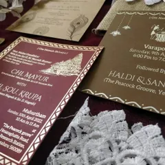 A detailed shot of our handmade jute invitation inserts. This card, for the Muhurtham ceremony, features traditional temple artwork with gold printing on a rich maroon background, blending rustic materials with cultural elegance.