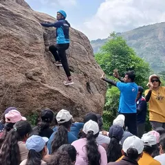 An instructor demonstrates a climbing move to an engaged audience of students at our Ramanagara rock climbing course.