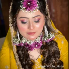 A close-up of the Haldi makeup. The eyeshadow has hints of pink and purple to match the flowers, and her skin is dewy and fresh.