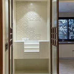 A look inside the beautiful home temple. The back wall features a custom CNC-cut corian panel with an intricate geometric pattern, and the platform is designed with steps for placing idols.