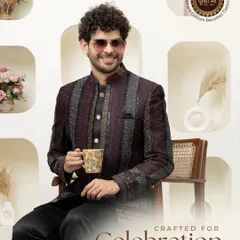 Crafted for celebration. A model enjoys a cup of tea while wearing a deep maroon, textured Bandhgala, showing that style and comfort can go hand in hand.