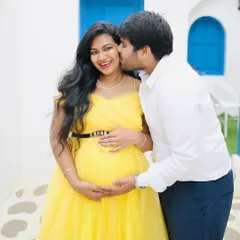 A sweet and candid moment captured during a couple's maternity shoot. The vibrant yellow of her tulle gown pops beautifully against his simple white shirt and dark trousers, a classic combination for a bright and happy theme.