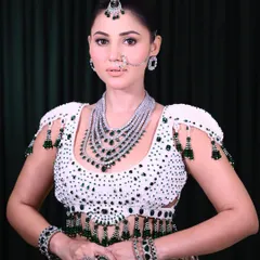 A full view of a modern bridal look, showcasing the detailed beadwork on the blouse and how the multi-layered diamond and emerald jewelry complements the makeup.
