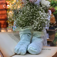 A playful and creative detail from the storybook shower. A pair of tiny baby socks, filled with delicate baby's breath, rests on an open book, symbolizing the little one who is the subject of this new chapter.