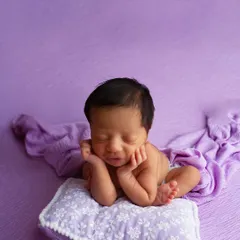 Another variation of the safe 'froggy pose', this time with the baby resting their head on a small pillow. This pose requires specialized training to execute safely.
