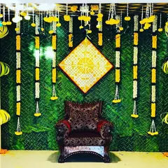 A backdrop featuring a woven green mat, vertical flower garlands, and a central hand-painted kolam art piece. This design blends rustic textures with traditional art for a unique look.