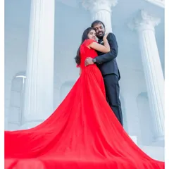 A powerful and romantic pose with the bride in a vibrant red flowing gown, creating a stunning contrast against the white palatial columns. This is a classic example of a high-fashion, cinematic pre-wedding photograph.