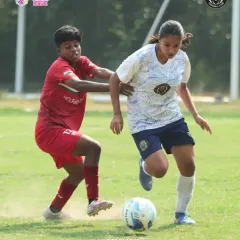 Driving forward with the ball. Our player pushes past a defender, showing determination and skill to advance the play up the field.