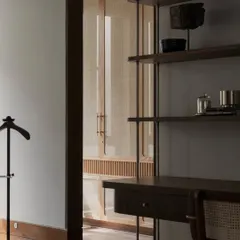 A detail shot from the Pràna house, showing a custom desk and shelving unit. The cane-fronted doors in the background add a layer of texture and warmth.