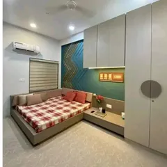 Another view of the same bedroom, showing the L-shaped bed design with an extended headboard that becomes a bedside table. This is a great way to maximize function in a compact space.