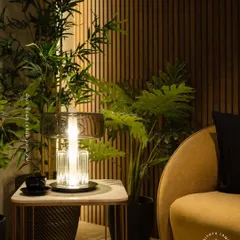 Our crystal and glass table lamp adds a touch of modern elegance to this cozy corner. Its clean lines and warm glow make it a perfect companion for a comfortable armchair, providing both style and function.