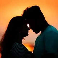 A close-up silhouette of a couple against a warm sunset sky, focusing on their connection.