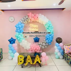 A beautiful pastel-themed birthday decoration for a home setting. The balloon ring features shades of blue, pink, and mint green, with a 'Happy Birthday' neon sign and custom foil letter balloons.