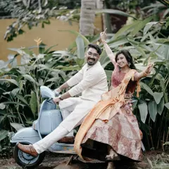 A fun and playful shot of a couple on a retro blue scooter, surrounded by lush greenery, perfect for a casual and quirky pre-wedding theme.