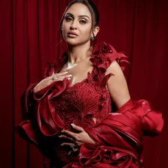 A powerful pose matched with equally powerful makeup. The focus here is on sculpted features and a radiant complexion against a dramatic red backdrop.