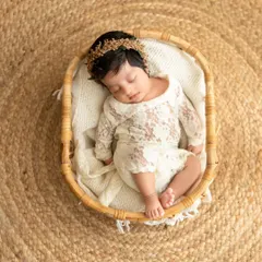An overhead shot of a sleeping newborn in a lace outfit, nestled in a rustic wicker basket on a jute rug. This highlights my use of natural textures and props.