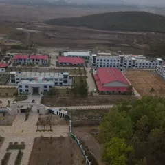 The UNACCO School campus under construction, showing the scale of the development and its location nestled between two hills.