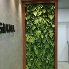 This elegant, wood-framed artificial green wall serves as a permanent art piece in a corporate hallway. The design exclusively uses various types of artificial ferns, creating a lush, uniform, and sophisticated look.
