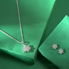 A delicate and modern silver-toned necklace set. The design features a simple floral pendant made of sparkling stones, with matching minimalist stud earrings.