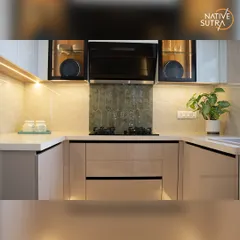 A close-up of the cooking area, featuring a sleek black chimney and an elegant backsplash. The combination of taupe cabinets, a white countertop, and glass-front upper cabinets creates a light and airy feel.