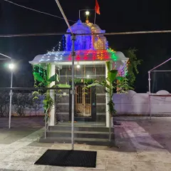 A small temple decorated for a night event with colorful lights, banana plantains, and simple leaf hangings.