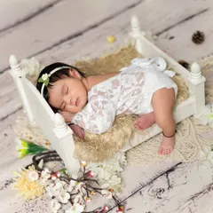 A sweet baby girl sleeping peacefully on a tiny wooden bed. We use delicate lace outfits and props to create timeless and classic newborn portraits.
