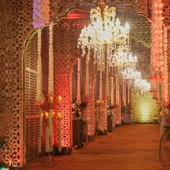 A closer look at the opulent corridor, where the warm glow from the chandeliers and candles reflects off the intricate golden jali screens.